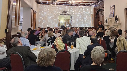 A group of people watch a speaker